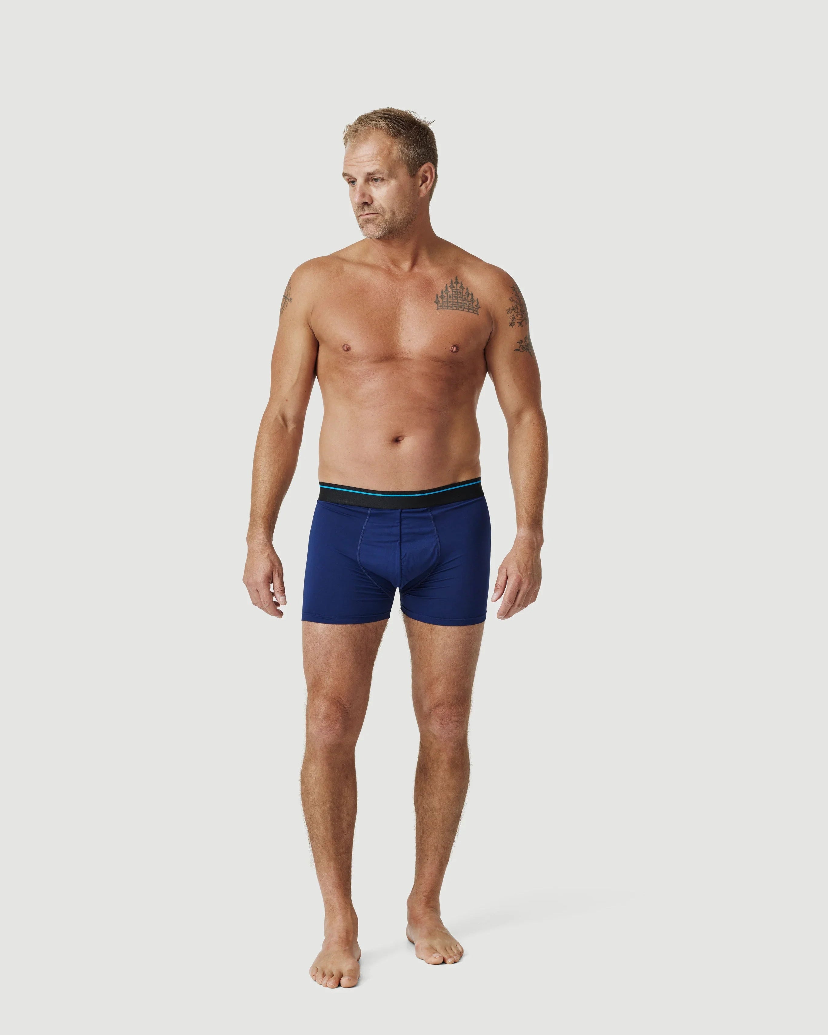 Man modeling blue boxer briefs against plain white background for men's underwear lookbook