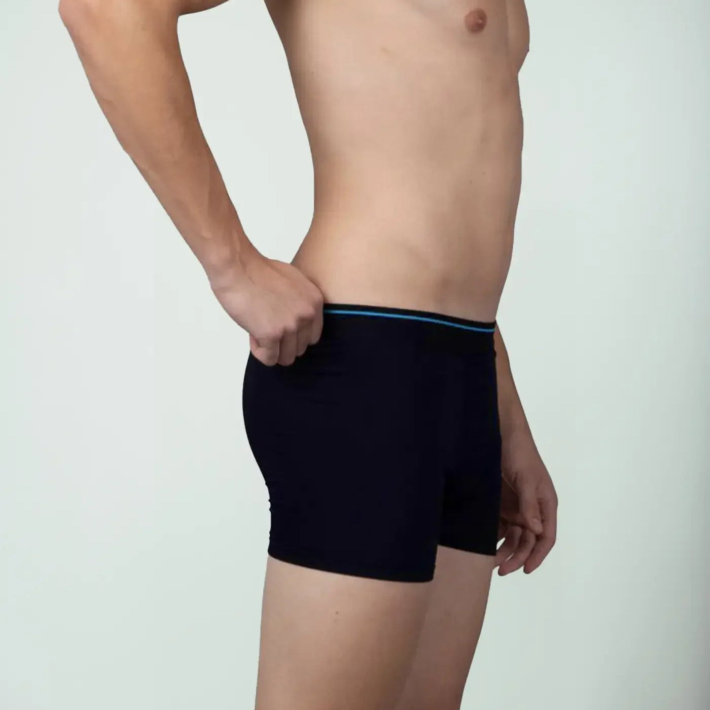 Side view of man wearing blue bamboo boxer briefs against plain background